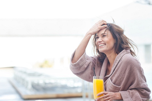 Woman at hotel poolside holding a glass of orange juice