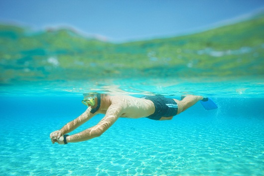 Snorkeling adventure. Young man diving into the sea. Over, under sea, split shot, half-half underwater turquoise lagoon.
